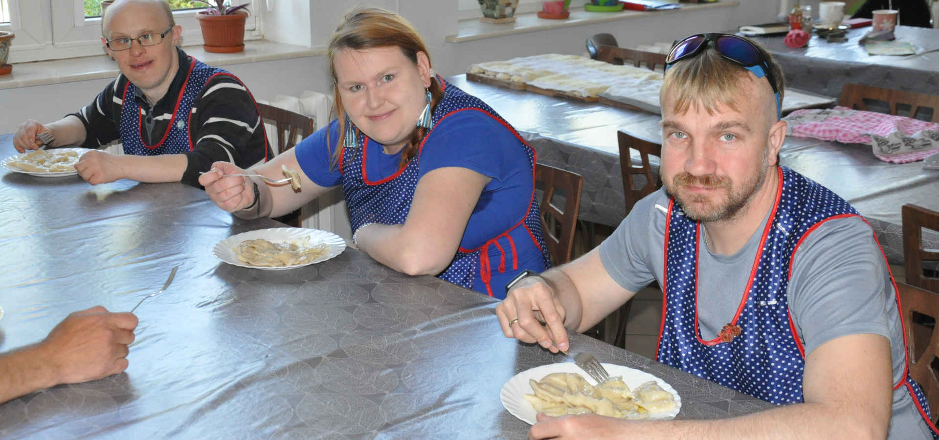Trzy osoby przy stole jedzą pierogi